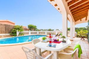 a patio with a table and chairs next to a pool at Villa Olga in Cala en Porter