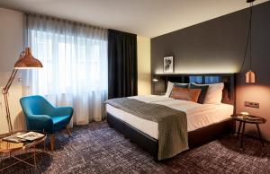 um quarto de hotel com uma cama e uma cadeira azul em Dom Hotel em Osnabrück
