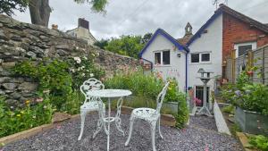 two white chairs and a table in a garden at Katie's Cottage in Church Stretton