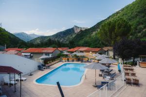 a swimming pool with umbrellas and tables and chairs at Hôtel Le Refuge des Sources in Digne-les-Bains