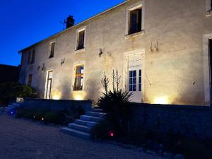 a large white building with stairs in front of it at Maison d'hôtes et gîte - Les 4 saisons de Manon in Tourtoirac