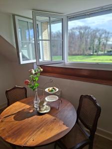 a wooden table with a vase of flowers and a window at C'est Si Bon in Vandenesse