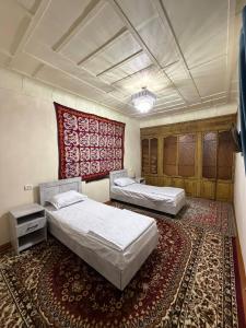 two beds in a room with a rug at Aziz Guest House in Samarkand
