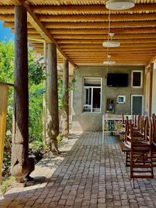 an outdoor patio with chairs and a wooden roof at Aziz Guest House in Samarkand