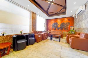 a waiting room with brown leather chairs and a large screen at Townhouse Oak Kozhikode Bus Stand Formerly Nextel Inn in Kozhikode