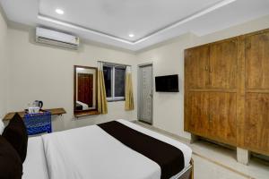 a bedroom with a bed and a large wooden cabinet at Super Townhouse Financial District Gachibowli Formerly Srinika Inn in Hyderabad