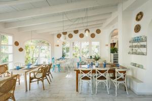 a dining room with tables and chairs and windows at MR Hotelet de la Raconà & Apartments in Denia