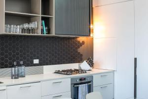 a kitchen with white cabinets and a stove top oven at Magnificent Apartment + FREE car park near CBD in Adelaide