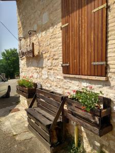 a wooden bench sitting outside of a building with flowers at Turris Morro di Rasiglia in Rasiglia