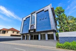 a building with a glass facade on a street at Townhouse Kozhencherry Formerly The Beige Hotel in Pathanāmthitta