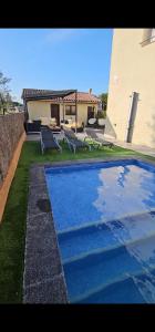a swimming pool with two chairs and a house at Villadora Piscina privada & jacuzzi Cerca de la costa brava in Santa Coloma de Farners