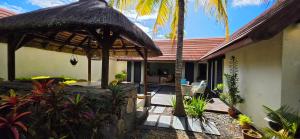 a house with a patio with a table and a straw umbrella at Villa 24 in Grand-Baie