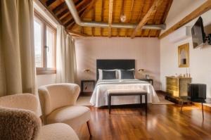 a bedroom with a bed and a tv and chairs at Casón del Conde in Orgaz