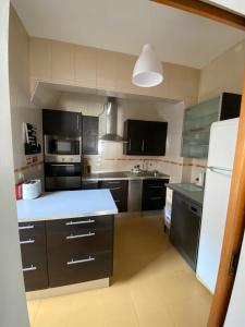 a kitchen with black cabinets and a white refrigerator at Casa Ferreira in Beja +7 photos