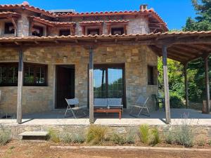 a stone house with two chairs on a patio at The Hill House in Argalasti