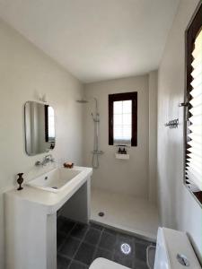 a white bathroom with a sink and a shower at The Hill House in Argalasti