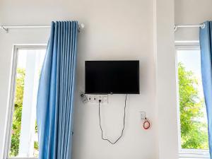a flat screen tv hanging on a wall next to two windows at Bungalow Gió Hát in Phú Quốc