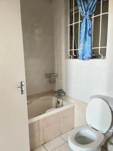 a bathroom with a toilet and a bath tub with a window at Margate Boulevard - Seaview Apartment in Margate