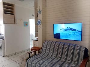 a living room with a couch and a tv on the wall at Beach Cottage Abigail in Southbroom