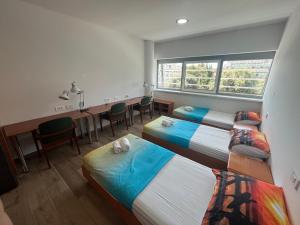 a room with two beds and a desk and a table at Motel Barka in Koper