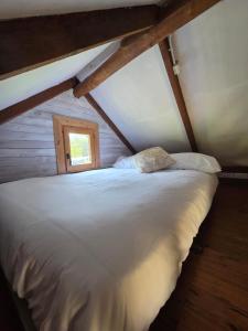 a white bed in a attic with a window at camping los pradones in Cudillero