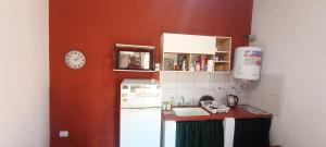 a kitchen with a white refrigerator and a red wall at Cabaña LDM cc in Santa Rosa
