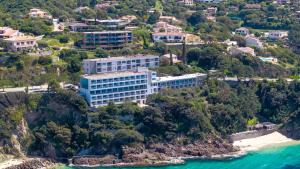a building on a hill next to the ocean at Hotel Roc E Mare in Propriano