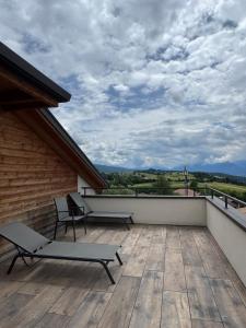 a balcony with two benches and a cloudy sky at Lady Maria Hotel Wellness & Resort in Fondo