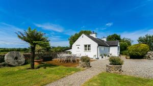 a white cottage with a table and chairs in the garden at Penrallt in Benllech