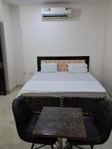 a bed in a room with a chair and a table at PLAY HOTEL PREET RESIDENCY couple friendly in Greater Noida +6 photos