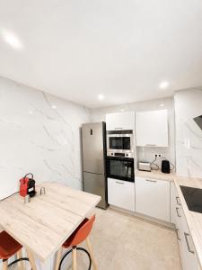 a kitchen with a wooden table and a refrigerator at Maison moderne Parking &Jardin in Narbonne