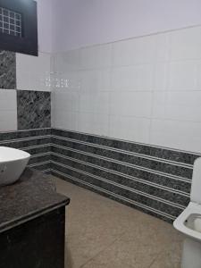 a bathroom with black and white tiled walls and a sink at PLAY HOTEL PREET RESIDENCY couple friendly in Greater Noida