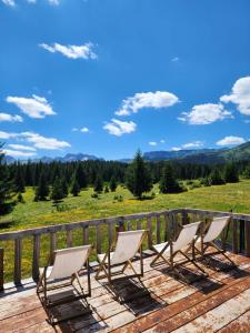 three chairs on a deck with a view of a field at Cottage Uskoci in Žabljak