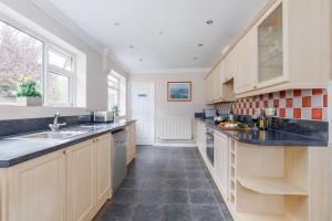 a kitchen with wooden cabinets and a black counter top at Talbot House by Grandeur Property in Bournemouth