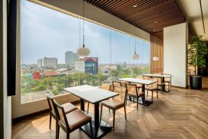 a restaurant with tables and chairs and a large window at Rich Palace Hotel in Surabaya