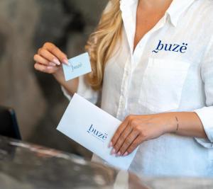 a woman holding two pieces of paper in her hands at Buzë Boutique Hotel in Sarandë