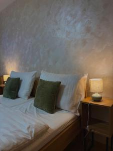 a bed with white sheets and green pillows on it at Penzion Tlustá kachna in Chrudim