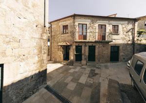 an old building with a car parked in front of it at Encanto do Lima Guest House By Lethes Legacy in Ponte de Lima
