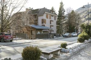 a house with a bench in front of a street at Bijoux Sozzine - AffittiPontediLegno in Ponte di Legno