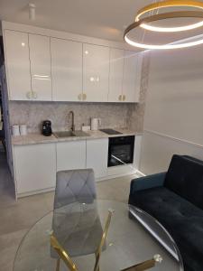 a living room with a glass table and a kitchen at GOLDEN HAUS Opole - Miss Gold & Mini Lux in Opole