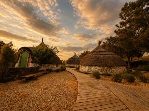 a row of huts with a bench and a sky at La Colibe, cătun arhaic ecologic in Corbu