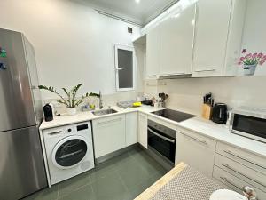 a kitchen with white cabinets and a sink and a dishwasher at Rooms Granvia in Barcelona
