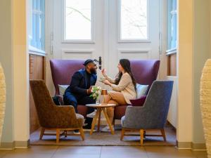 a man and woman sitting in chairs in a room at Mercure Hotel Hannover City in Hannover