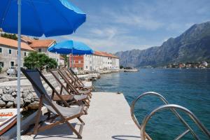 a group of chairs and umbrellas on a dock with the water at Historic Waterfront Apartment in Muo