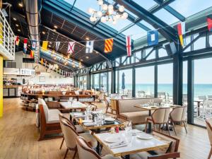 a restaurant with tables and chairs with the ocean in the background at Côte Ouest Thalasso & Spa Les Sables d'Olonne - MGallery Collection in Les Sables-d'Olonne
