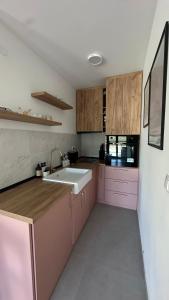 a kitchen with pink cabinets and a sink at Eirene Residence in Vrnjačka Banja