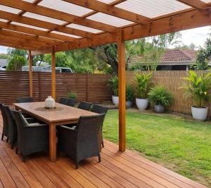 a wooden deck with a table and chairs under a pergola at Barnard Beach House in Broadwater