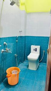 a bathroom with a toilet and an orange bucket at RASHI Lodge Attibale in Attibele
