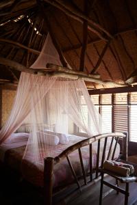 a bedroom with a canopy bed with mosquito nets at The Island Houses Bingin in Uluwatu