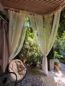 a pergola with curtains and a bed on a patio at Lux Beba Pancevo in Pančevo